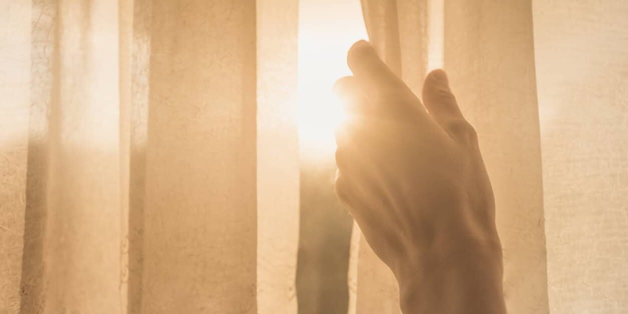 Woman hand opening curtains in the bedroom